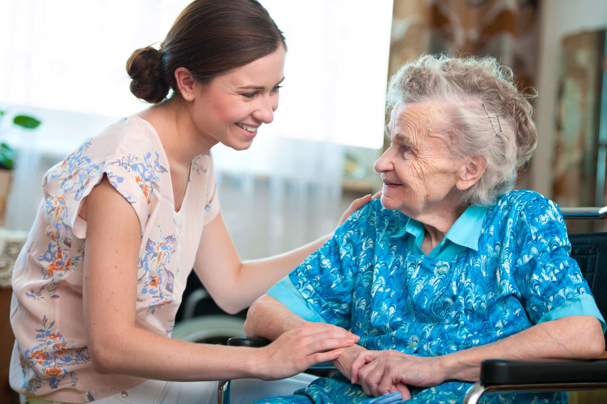 Young woman supporting elderly caregiver, promoting mental health in caregivers