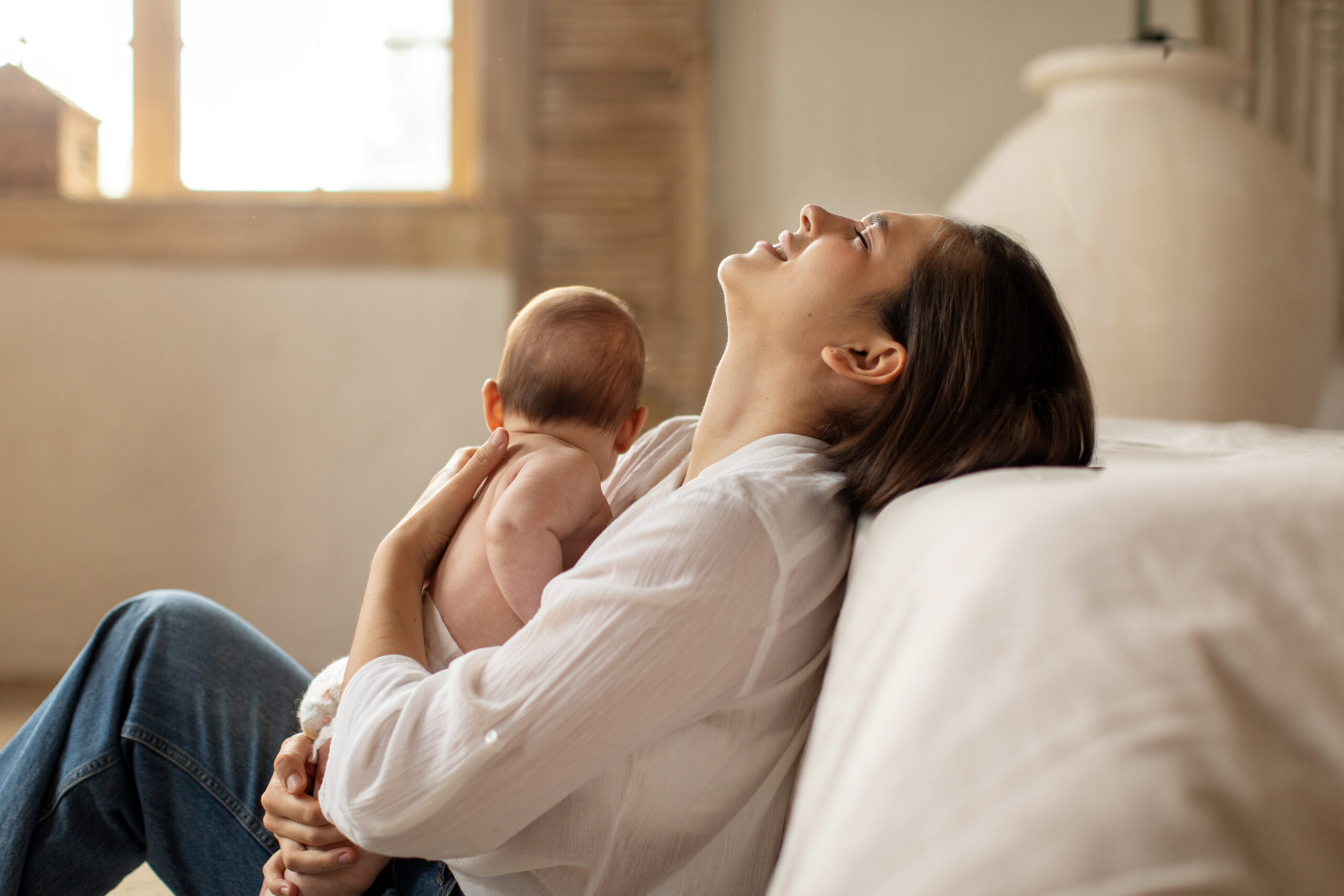 Mother with postpartum depression and anxiety holding her newborn baby at home