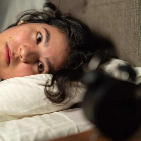 Stressed young woman having insomnia lying in bed at night, suffering from sleep disorder and looking worried
